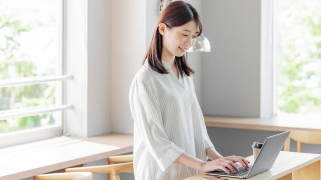 自宅で笑顔でパソコンを使う若い女性