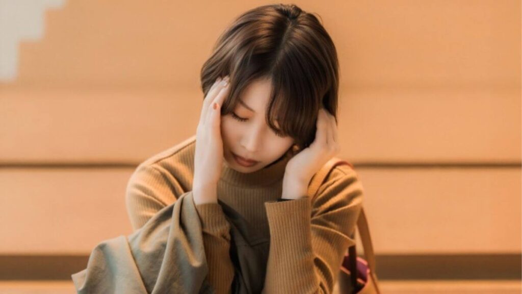 階段で頭を押さえる若い女性