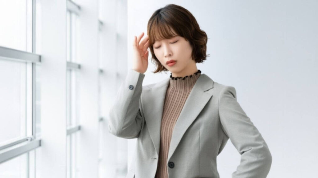 疲れすぎて頭痛がしているスーツ姿の若い女性