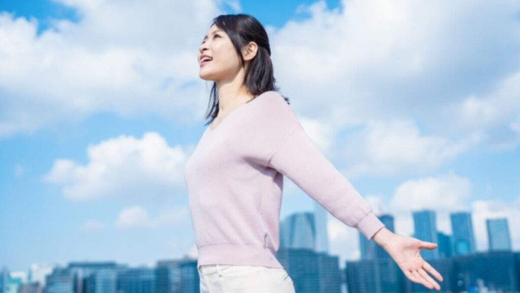 外で手を広げリラックスする若い女性